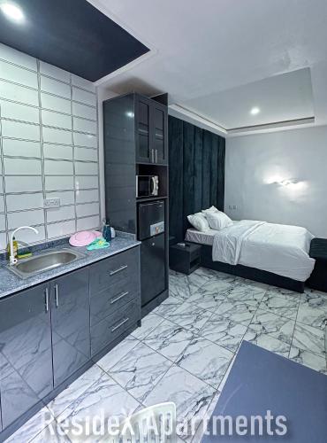 a kitchen with a sink and a bed in a room at ResideX Apartment in Jidu