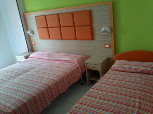 カットーリカにあるHotel Consulの緑とオレンジの壁の客室で、ベッド2台が備わります。