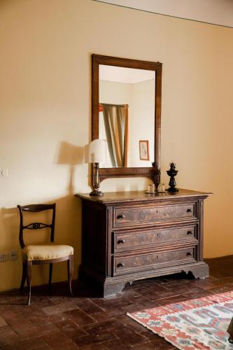 a dresser with a mirror and a chair in a room at Castello in Lucignano