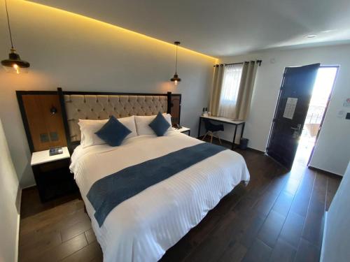 a bedroom with a large bed with white sheets and blue pillows at Hotel Boutique Casa Loreta in Querétaro