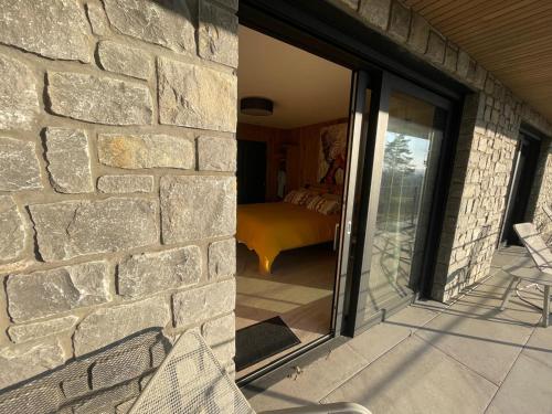 a stone wall with a sliding glass door to a bedroom at Point de Vue Caleste in Wellin