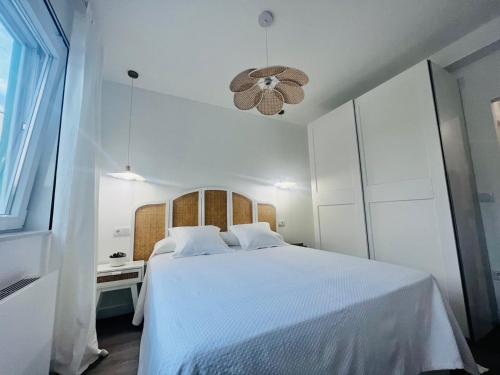 Habitación blanca con cama blanca y lámpara de araña. en Villa Turquesa B, en Viveiro