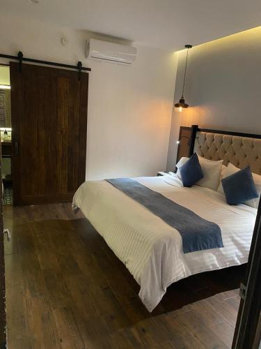a bedroom with a large white bed with blue pillows at Hotel Boutique Casa Loreta in Querétaro