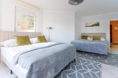 a white bedroom with two beds and a window at Luxury Villa with Indoor Pool, Jacuzzi, Sauna & Breathtaking City View in Klosterneuburg