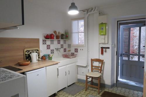 une cuisine avec des armoires blanches et une table et une chaise dans l'établissement BELESTAGITE7 Pays Catalan 66, à Bélesta