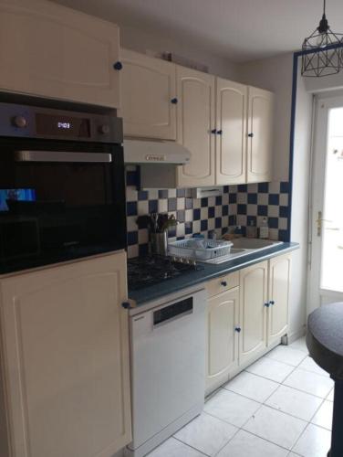 une cuisine avec des armoires blanches et des appareils noirs dans l'établissement Maison avec courette à 400 m de la plage, à La Bernerie-en-Retz
