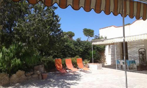 a group of chairs and an umbrella on a patio at VillA LA PinetA in Favignana