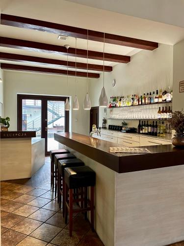 a kitchen with a bar with black stools at Hotel Beskid in Milówka