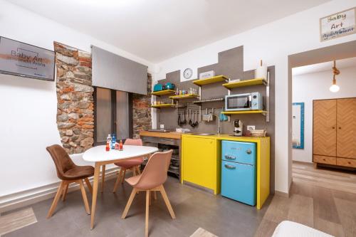 a kitchen with a table and a yellow and blue refrigerator at Baby Art Apartment in Arona