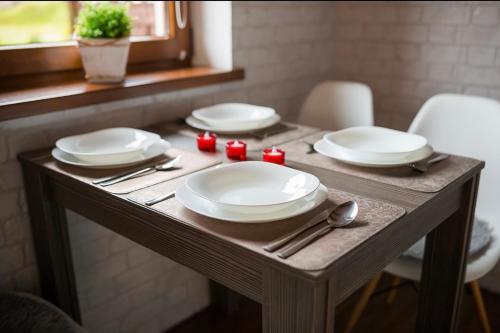 a wooden table with plates and utensils on it at Domki Irena Kozdrowska in Polańczyk