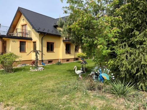 a yellow house with two birds in the yard at Agro u Murzyna in Sienno