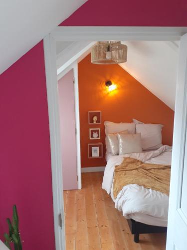 une chambre avec deux lits et un mur orange dans l'établissement Le Logis d'Hermione, à Caden