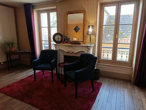 a living room with two chairs and a fireplace at B&B Girolles les Forges in Girolles