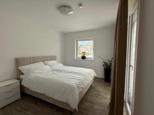 a white bedroom with a bed and a window at Ferienwohnung am Schlosspark in Altmünster