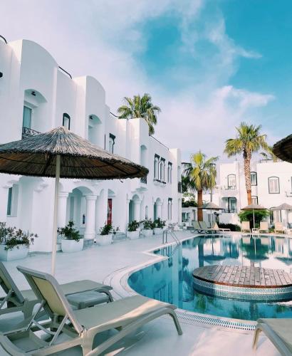 a pool at a hotel with chairs and an umbrella at Yalinn Boutique Hotel in Yalıkavak