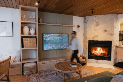 a man walking through a living room with a fireplace at BÕSKI - Refuge de luxe in Stoneham