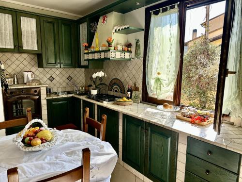a kitchen with green cabinets and a table with a bowl of fruit at Casa Lorenzo Vicopisano in Vicopisano