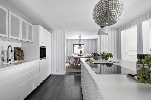 a kitchen with white cabinets and a large chandelier at Cozy vacation home very close to the beach in Tisvilde