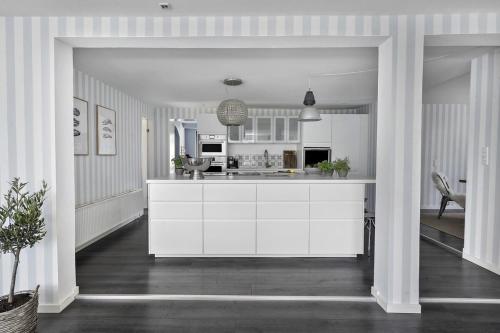 a kitchen with white cabinets and a kitchen island at Cozy vacation home very close to the beach in Tisvilde