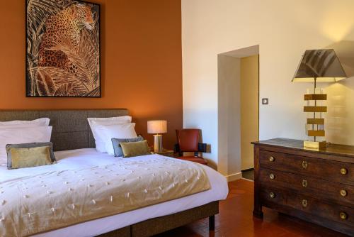 a bedroom with a bed and a dresser and a mirror at Palais Aoma, hôtel particulier de luxe en Provence in LʼIsle-sur-la-Sorgue
