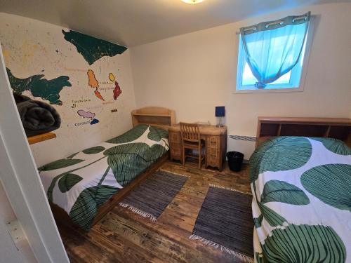 a bedroom with two beds and a desk and a window at Auberge Internationale Le Tangon in Sept-Îles
