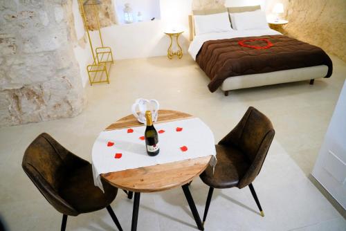 a bedroom with a table with a bottle of wine on it at Dimora Antica Falegnameria - tra STORIA e RELAX in Ostuni