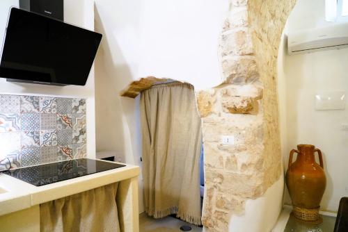 a bathroom with a shower curtain and a television at Dimora Antica Falegnameria - tra STORIA e RELAX in Ostuni