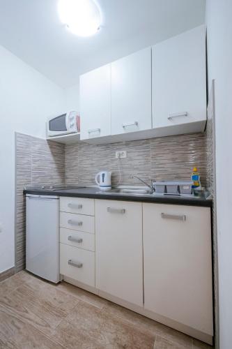 a kitchen with white cabinets and a sink at APARTMANI EMA in Zadar
