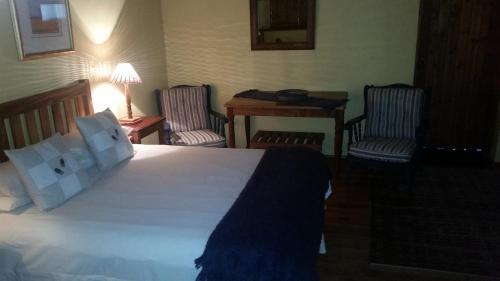 a hotel room with a bed and two chairs at Over The Mountain Guest Farm in George