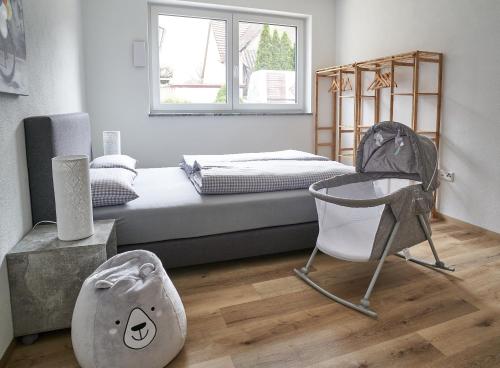 a bedroom with a bed and a baby chair at Ferienwohnungen Auf der alten Gärtnerei GmbH in Günzburg