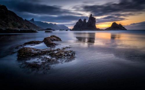 a sunset on a beach with rocks in the water at Casa ADOLFO in Almáciga