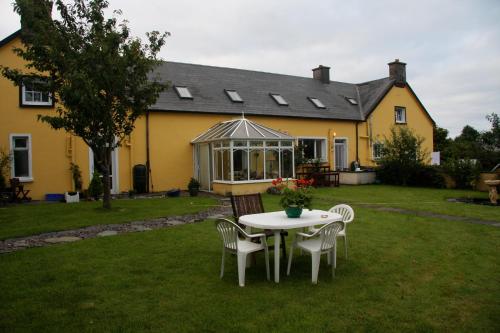 a table and chairs in front of a yellow house at The Old School House B&B in Ballinskelligs