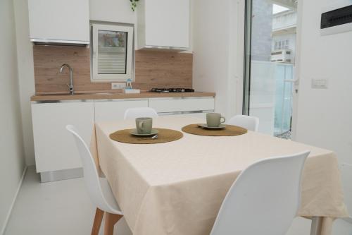 a white kitchen with a table with two cups on it at Lmholiday SUNSET apartment in Torre Canne