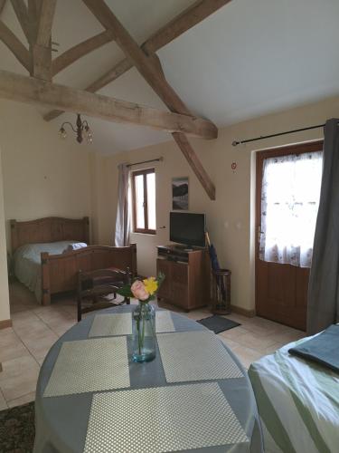 Una sala de estar con una mesa y un dormitorio. en Le Chemin des Hêtres, en Armaillé
