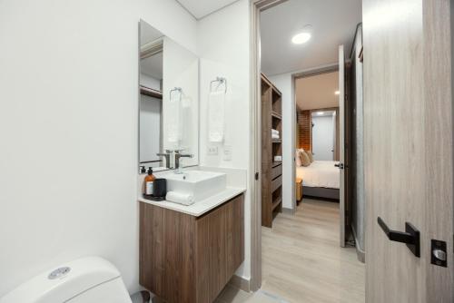 a bathroom with a sink and a toilet and a bed at Kyux Studios by MOME in Medellín