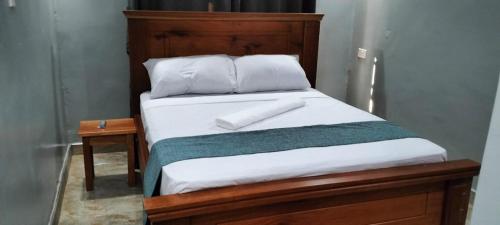 a bed with a wooden headboard and white pillows at Tamarind Breeze House in Mariakani