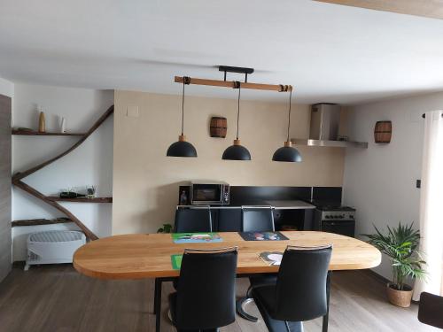 une cuisine avec une table en bois et des chaises noires dans l'établissement Winstub du vigneron, à Albé