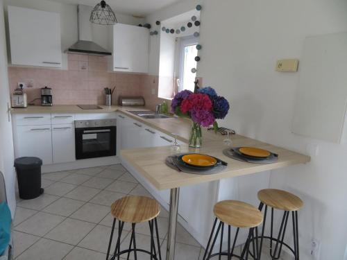 d'une cuisine avec une table avec des assiettes et des fleurs. dans l'établissement Gîte Pitouchig proche Golfe du Morbihan, à Pluneret
