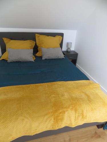 - un lit avec une couverture jaune et 2 oreillers dans l'établissement Gîte Pitouchig proche Golfe du Morbihan, à Pluneret