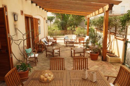 eine Außenterrasse mit Stühlen, Tischen und einem Tisch in der Unterkunft Casa Al Mare Sole e Relax in San Vito lo Capo