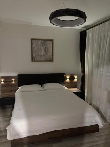 ein Schlafzimmer mit einem weißen Bett mit einem schwarzen Kopfteil in der Unterkunft DOL House - Apartment in Râșnov