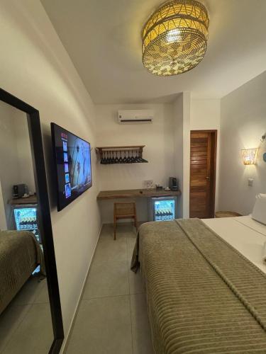 a bedroom with a bed and a table and a television at Pousada Amazing Jeri in Jericoacoara