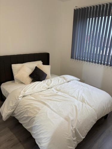 a bed with white sheets and pillows in a bedroom at Jay3 Suites - Spacious Entire Apartment in London in Dagenham