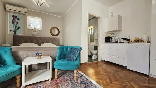 a bedroom with a bed and two blue chairs at Adria Apartments and Rooms in Dubrovnik