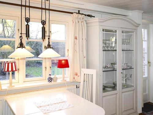 a kitchen with white cabinets and windows and a table at Ferienwohnung in Oevenum auf Foehr in Oevenum