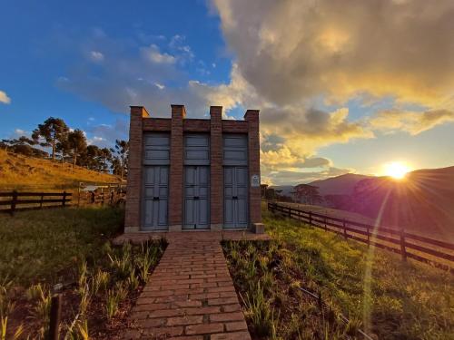 a tiny house in a field with the sunset in the background at Monte Sião Château in Urubici