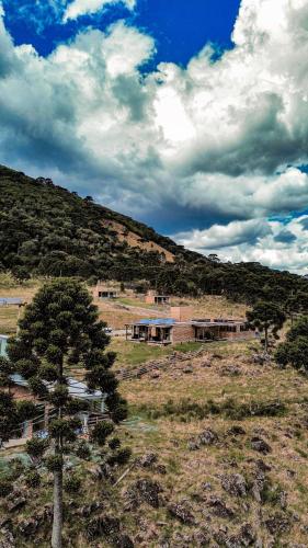 a building in the middle of a field with a tree at Monte Sião Château in Urubici
