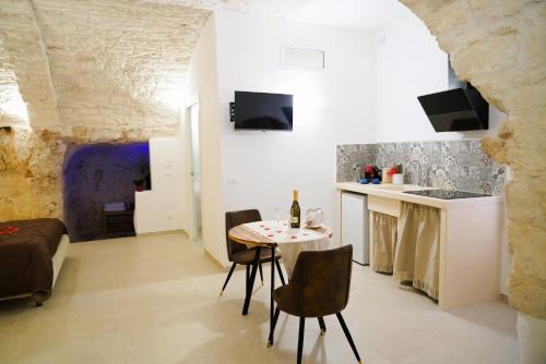 a living room with a table and chairs and a kitchen at Dimora Antica Falegnameria - tra STORIA e RELAX in Ostuni
