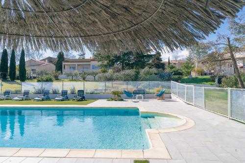 - une piscine avec des chaises et un parasol de chaume dans l'établissement Les Gîtes de Ginestas, à Ginestas