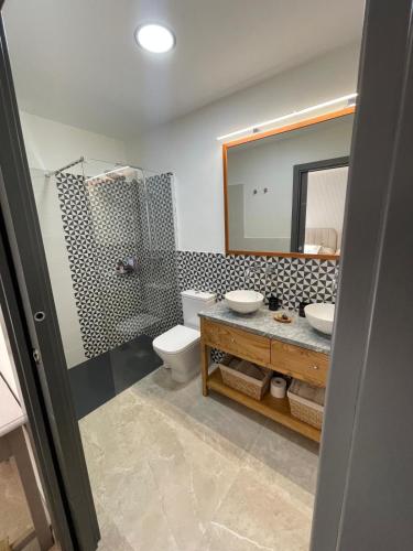 a bathroom with a sink and a toilet and a mirror at La Portilla de la Vera in Collado